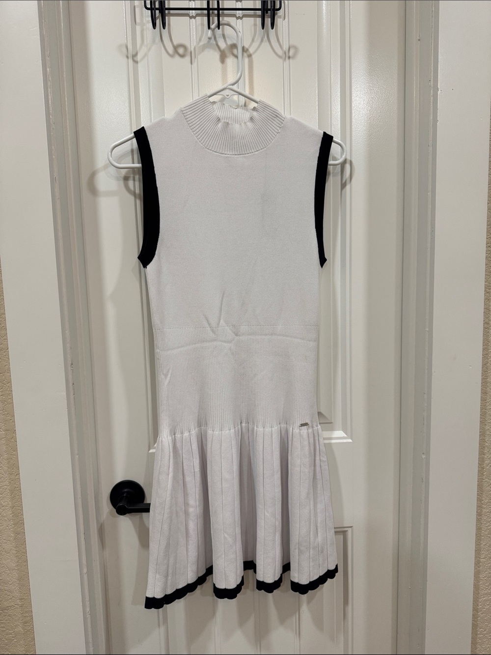 Sleeveless White Knit Dress with Black Trim and Pleated Hem